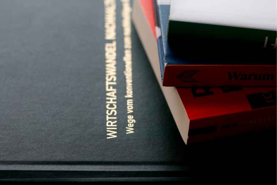 Gebundene Dissertation „Wirtschaftswandel Nachhaltigkeit – Wege vom konventionellen zum nachhaltigen Unternehmen” neben einem Stapel Fachbücher