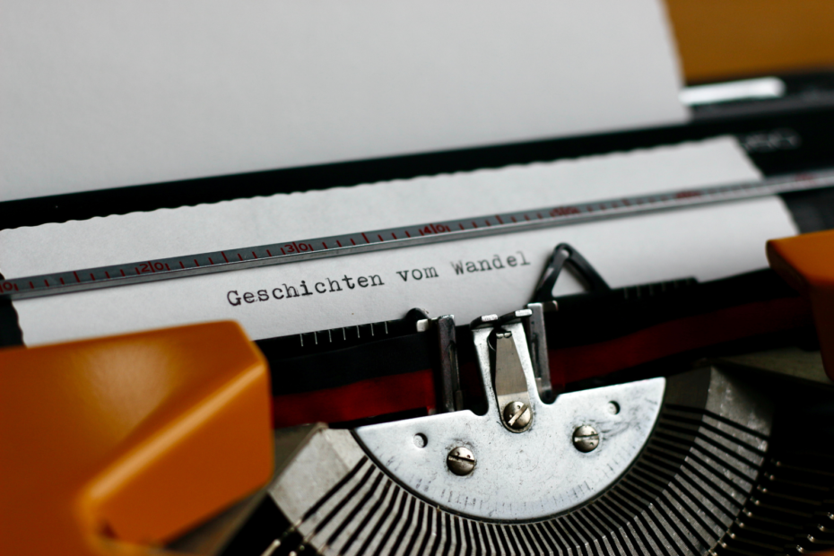 Schreibmaschine mit eingespanntem Papier, auf dem „Geschichten vom Wandel” getippt ist